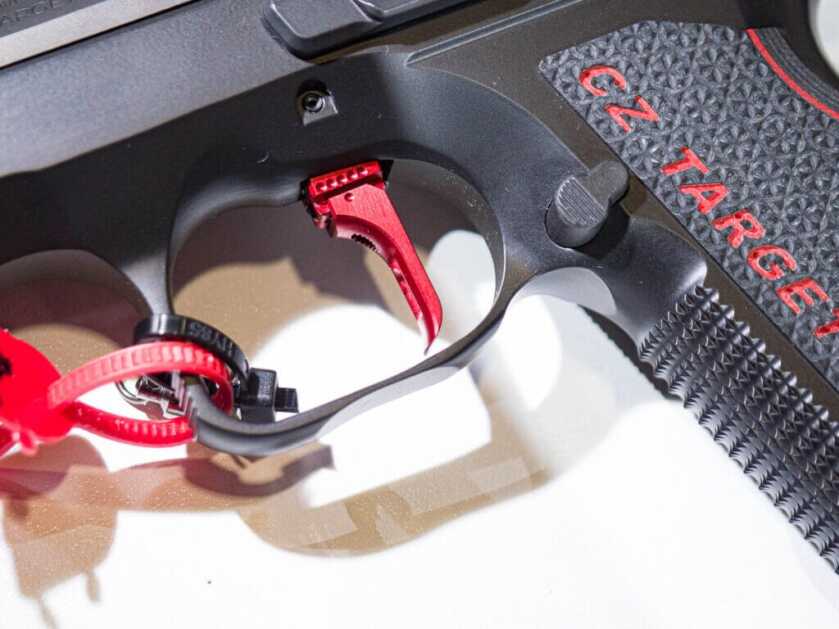 Close up view of the left side of the gun's trigger guard showing the red trigger.