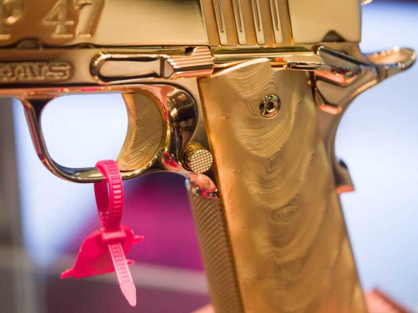 Close up view of the pistol's trigger and grips which are Damascus steel plated in gold.