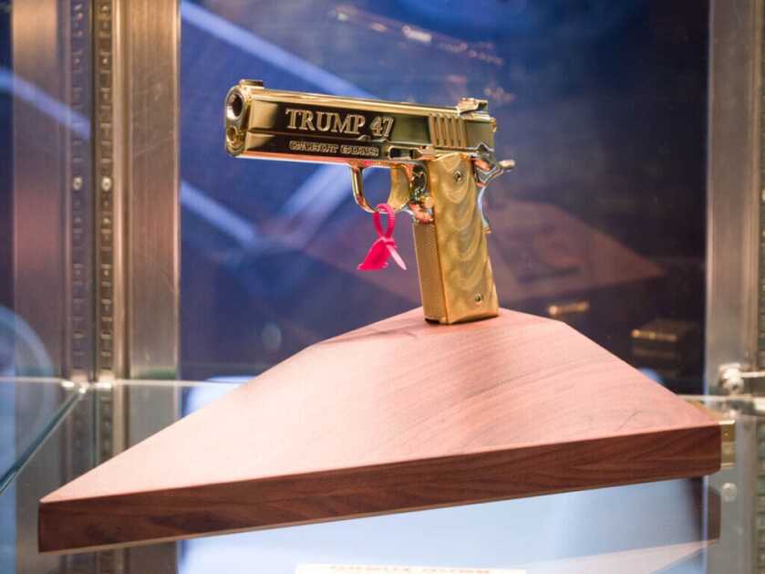 The pistol is mounted to a walnut stand facing to the left