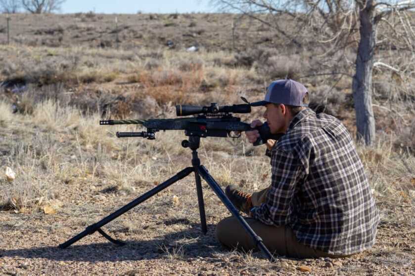 man shooting rifle on tripod