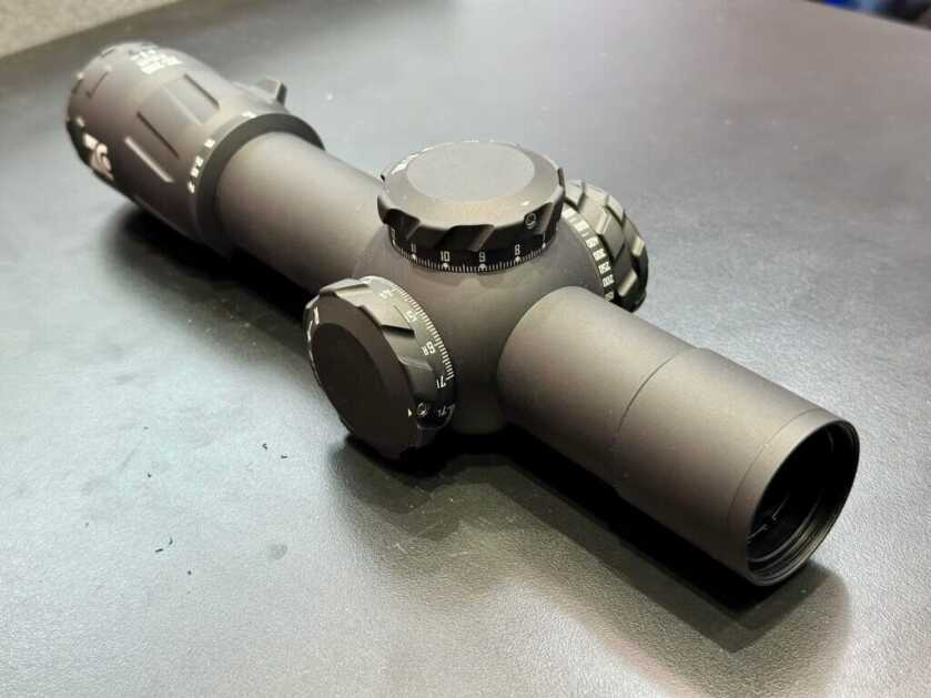 A precision optic is photographed on a black backdrop.