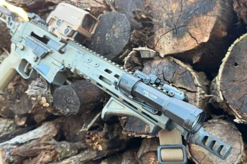 Holosun RAID mounted to decked out rifle on log pile