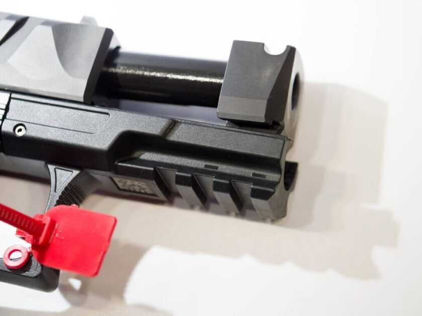 Close up of the fron of the gun, facing right, with the slide open showing the ported barrel device and pic rail.