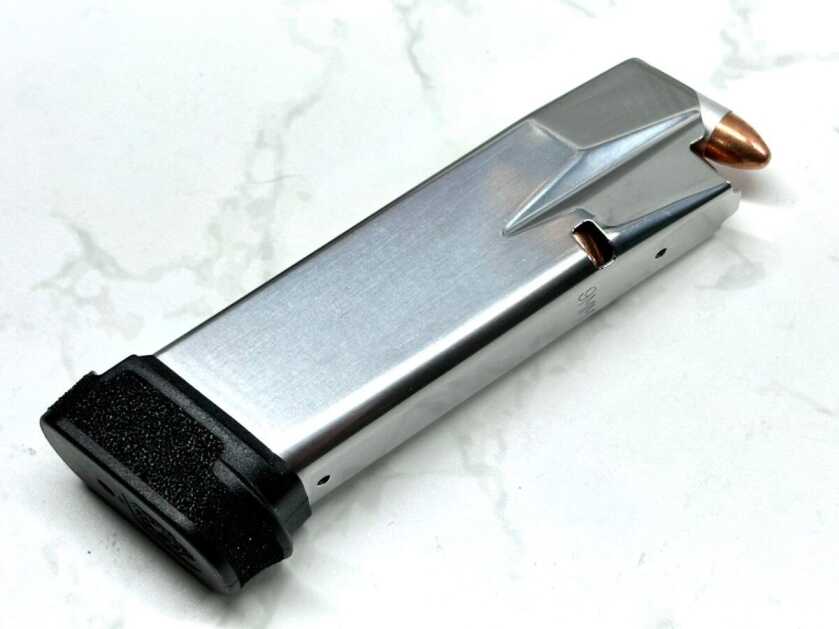 A loaded Hellcat Pro extended magazine lays on a white granite table top.