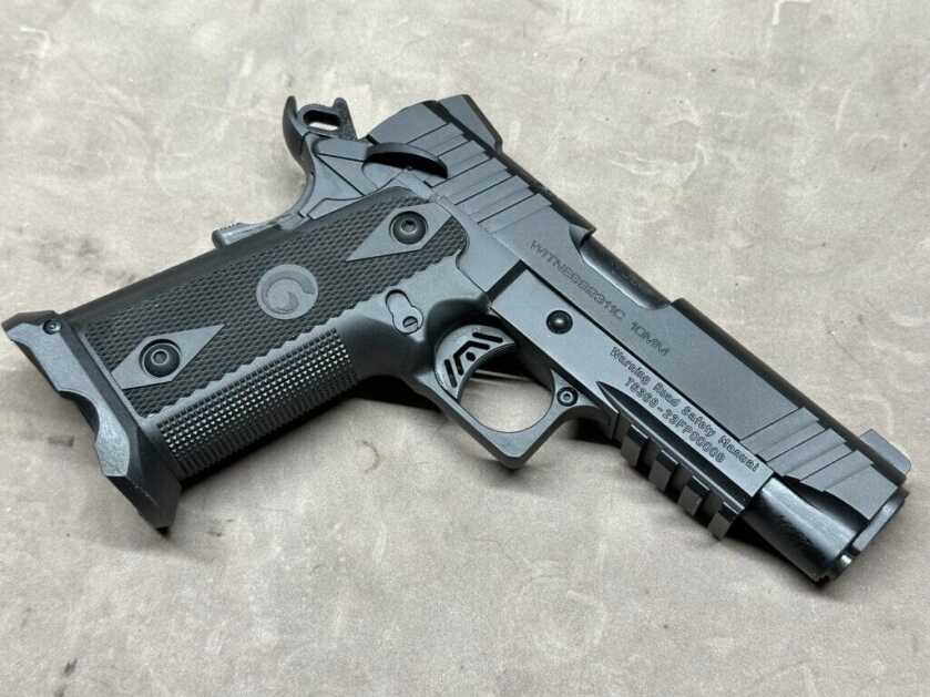 A black Girsan Witness2311 handgun is posed on a tan tabletop.