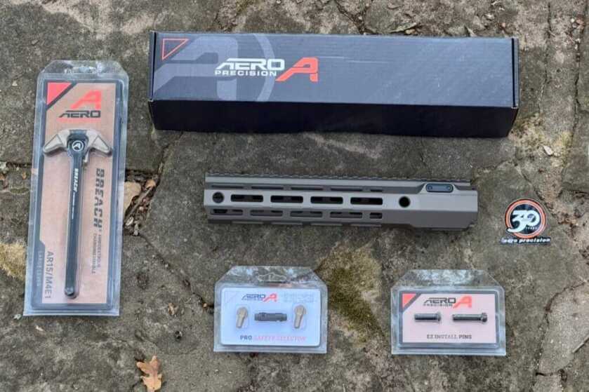 Aero Precision new AR charge handle hand guard safety set laid out on stone ground