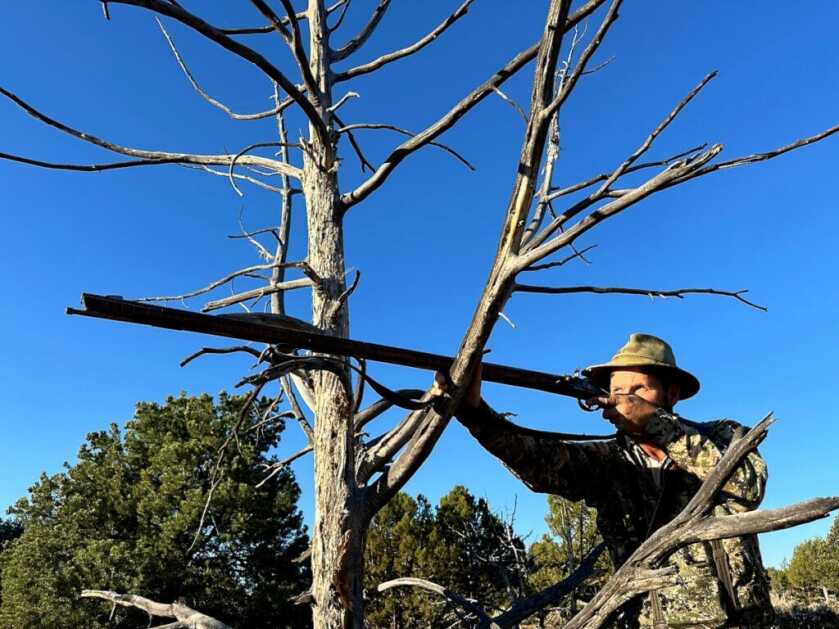 Flintlock mule deer hunt in Utah high desert with shooter braced on dead juniper for a 57-yard shot