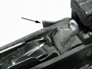 When the magazine runs empty, the follower presses up on a small tab (white arrow) and causes an internal last shot hold-open (black arrow) to lock the slide in the open position.