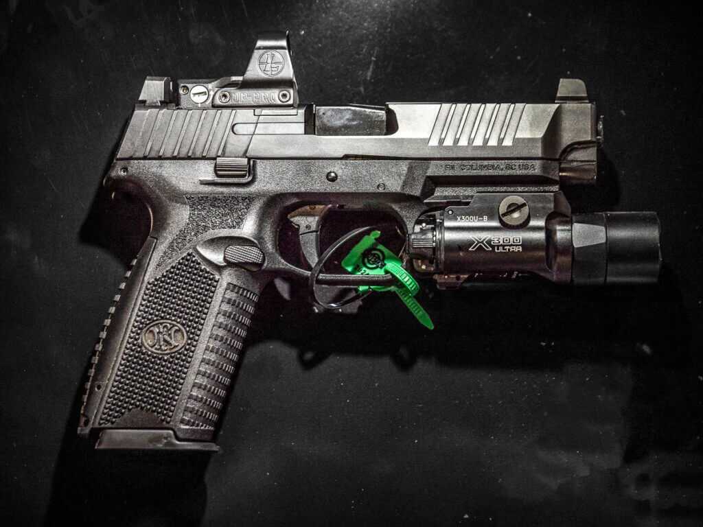 Full view of the 509 Full-size MRD pictol in black with red dot on top and a flashlight underneath. The gun is pointed to the right.