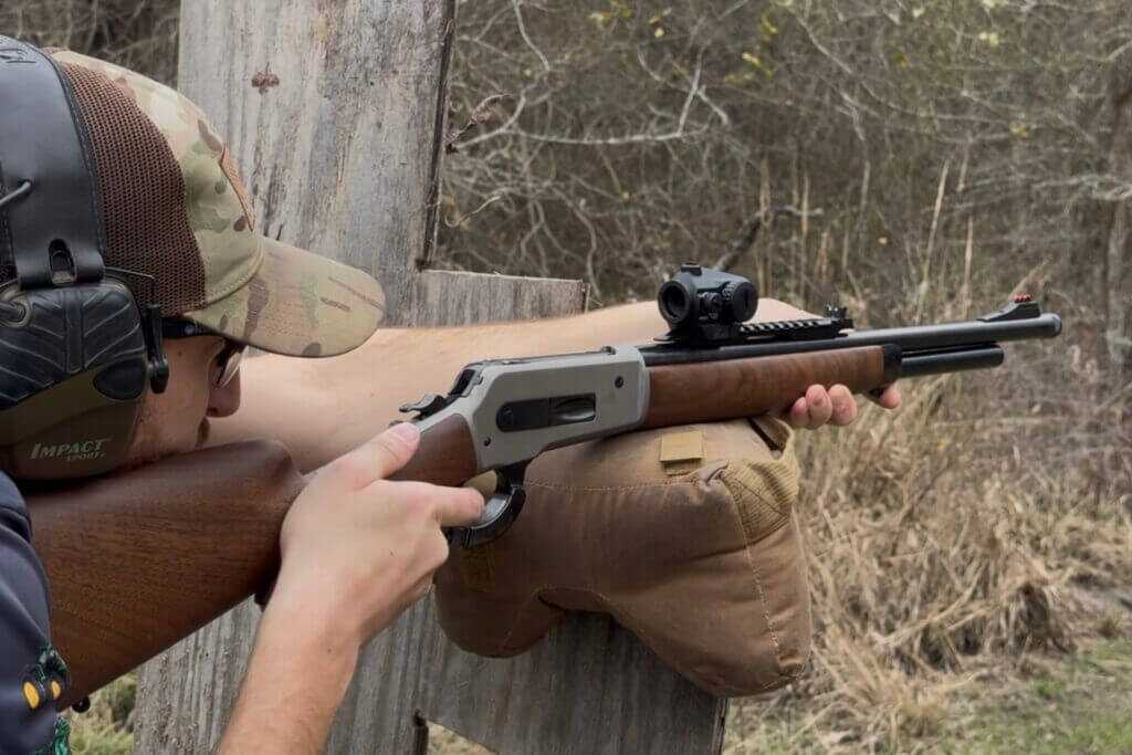Shooter holding rifle mounted with Vortex Crossfire green dot, ready to fire