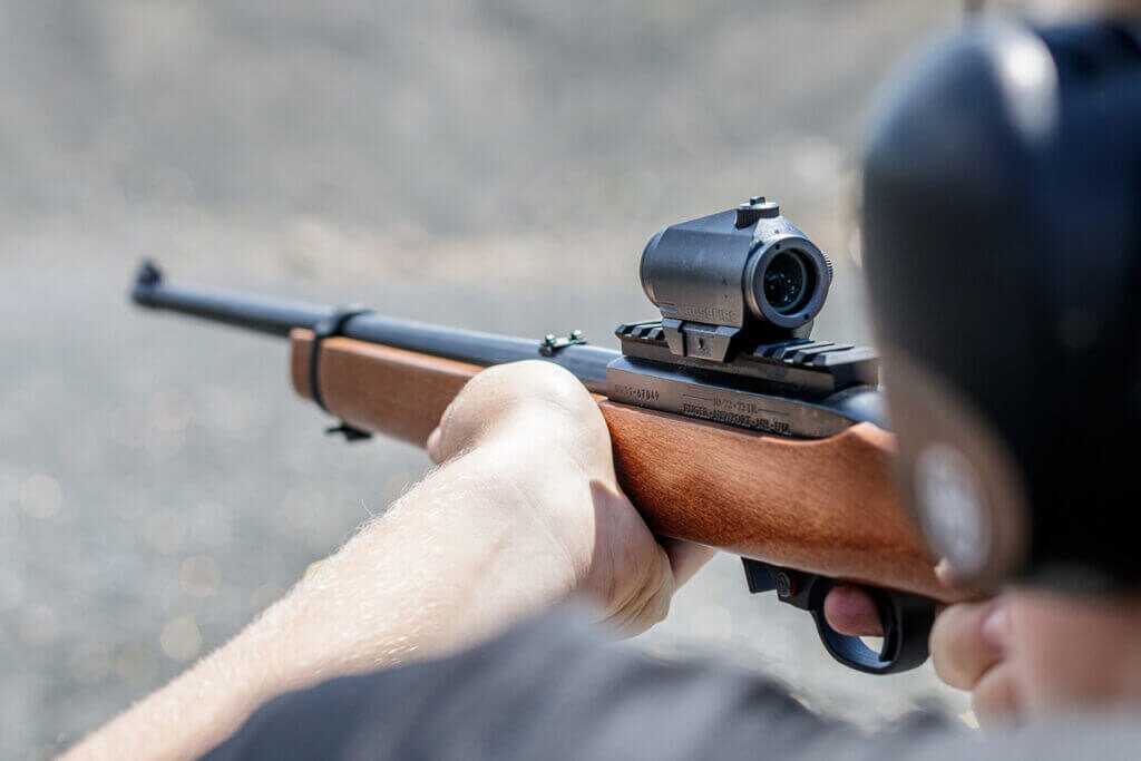 man shooting a rifle with a mounted optic