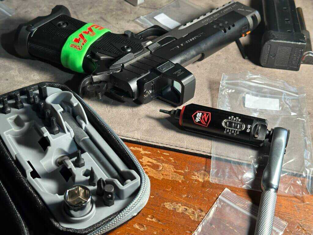 A Smart-Torq wrench lays next to a pistol with a freshly-installed red dot optic.