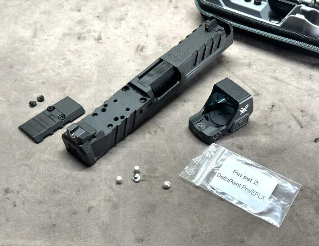 Pistol parts are laid out on a tan table top. A red dot sight is being mounted.