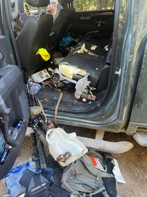 Open truck doors with gear visible, bow and pack after hunt near Montana trailhead