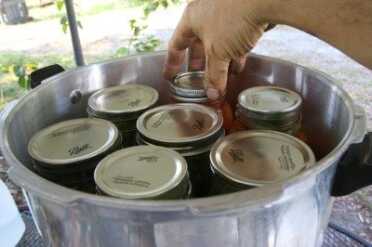 Put the flat caps on the jars and then the rings, which you screw in to fingertip tight. When the canner comes up to pressure, the air will be expelled from inside the jars, and on cooling a vacuum will be formed by the seal on the single use cap. The rings can then be removed and reused next time.  The four jars in the front are the wide mouth jars, and the three in the back are the standard mouth. 