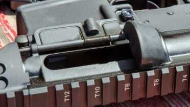 Modifications to accommodate 9mm include an enlarged ejection shield and a trimmed dust cover.