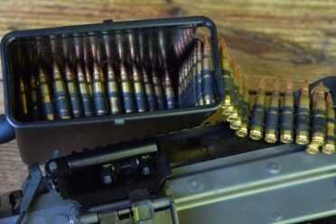 The belt of ammunition is held inside a plastic box that is located under the gun.