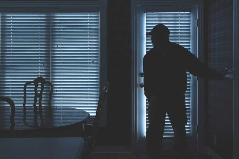 Burglar Breaking In To Home At Night Through Back Door