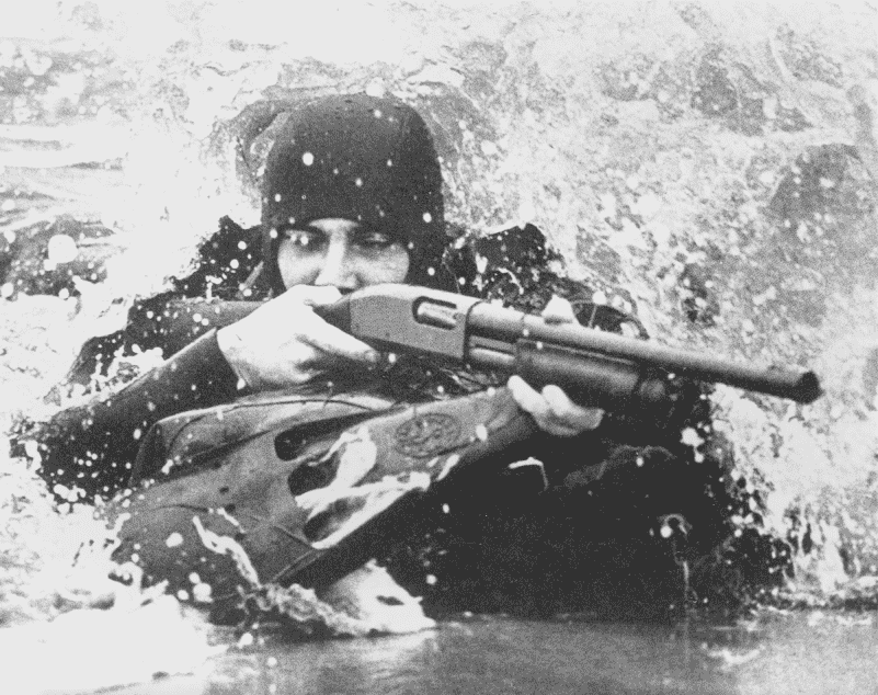 The Remington 870 saw use with the US military in the Vietnam and post-Vietnam eras. An M870 Riot Gun is shown in use here with a U.S. Navy SEAL.