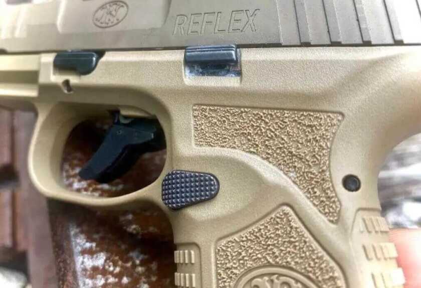 Aggressive checkering on the FN Reflex 9mm's magazine release aids reliable operation.