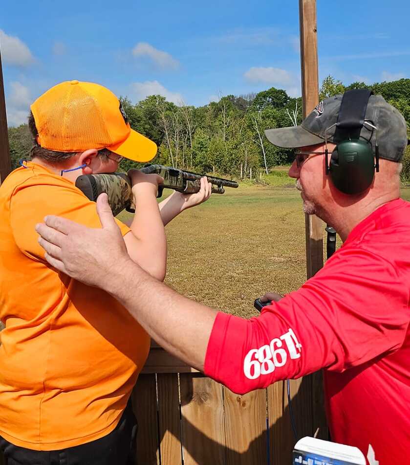 A youngster learning how to shoot a shotgun.