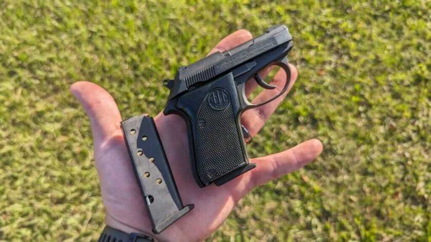 Beretta Tomcat sitting with extra loaded magazine on human palm