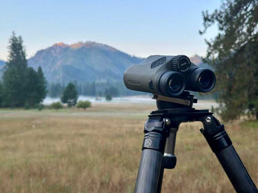 Binoculars on a tripod with the mountains in the background.