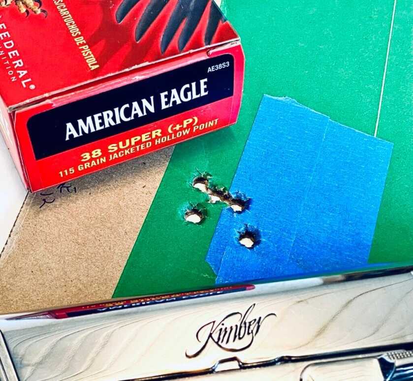 Kimber handgun on green and blue target with bullet holes