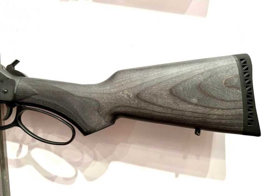 Closeup look at the wooden laminate buttstock of a rifle.