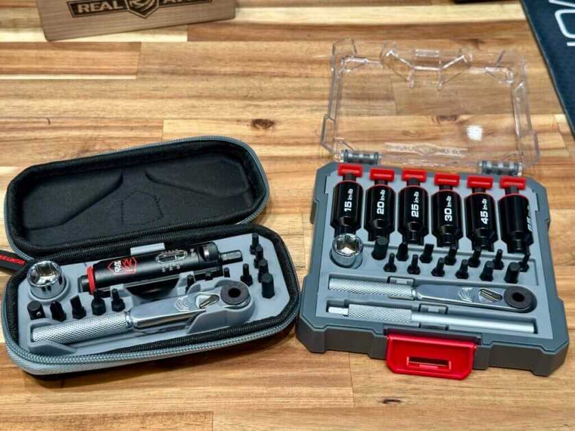 Two tool kits are on display on a wooden, butcher block table. 