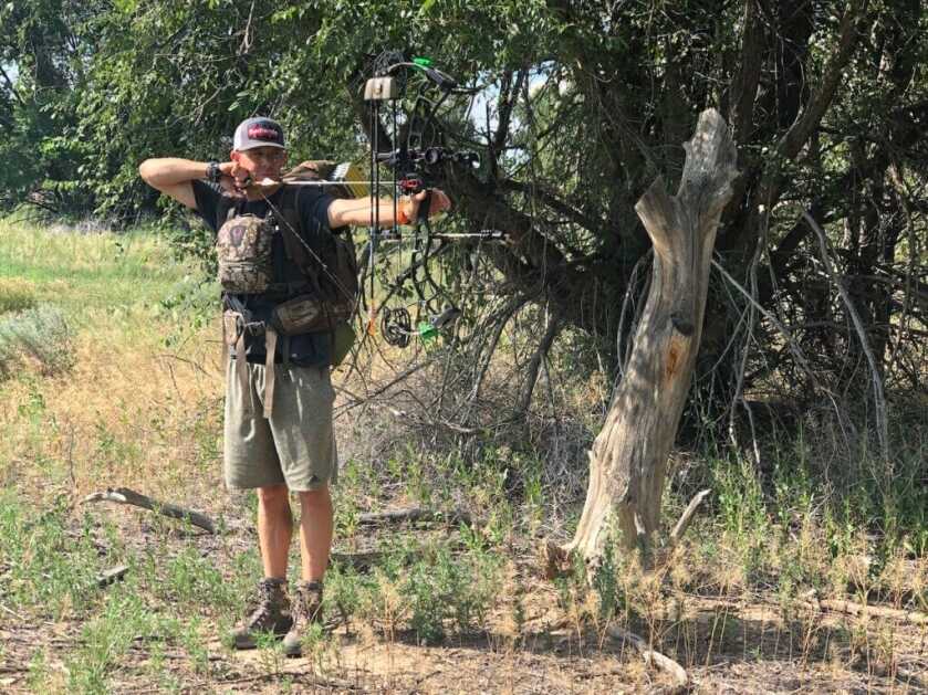bowhunter aiming a compound bow near trees while practicing to beat target panic