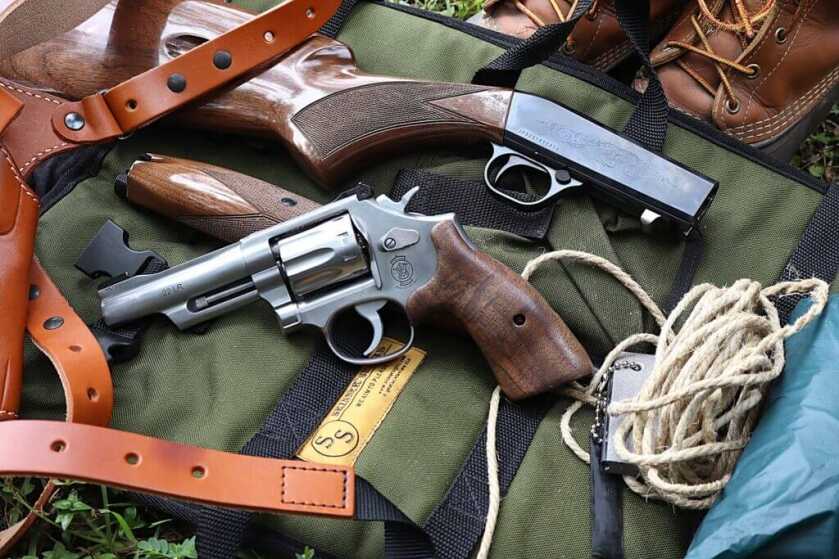 Smith & Wesson 617 Mountain Gun .22 LR revolver with Browning SA-22, rope, flint striker, holster, and poncho