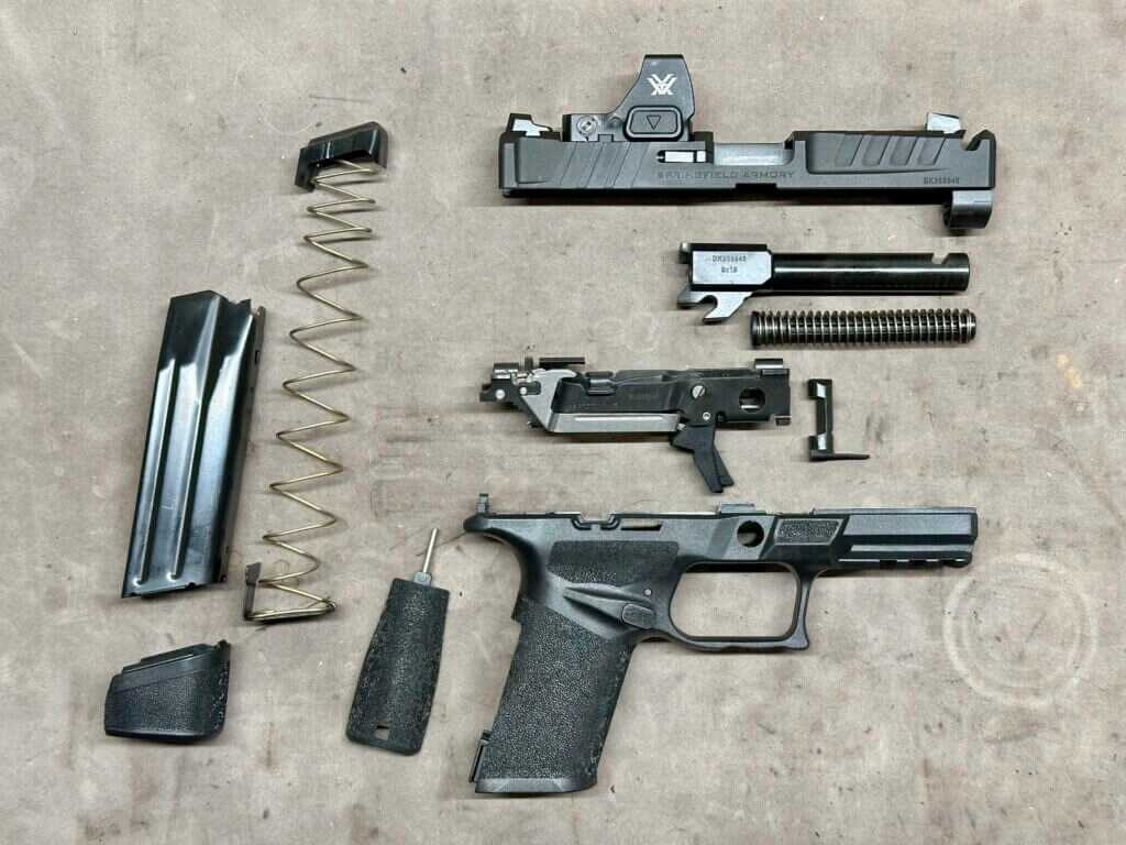 Disassembled completely, a handgun is laid out on a tan tabletop.  Echelon 4.0C Comp
