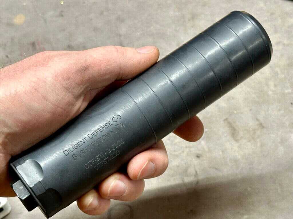 A black metal tube is being held in a man's hand.