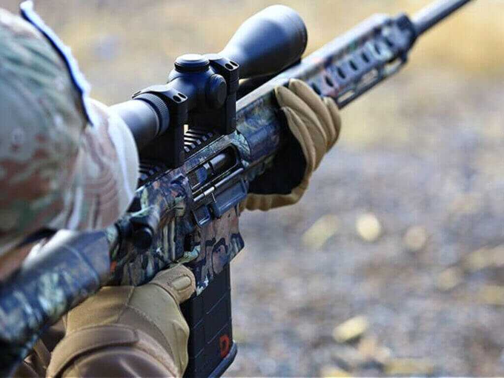 Hunter shooting an AR platform rifle during a field hunt