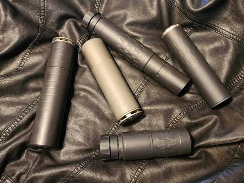 Assorted suppressors for home defense setups laid out on a bench