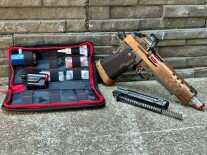 A handgun is posed next to a parts kit that converts the gun to run on CO2.