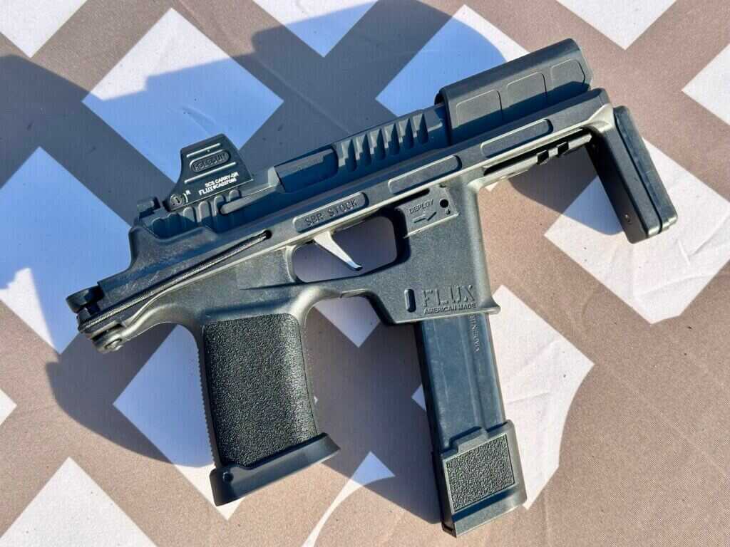 A PDW with a folded stock lays on a brown and white tabletop.