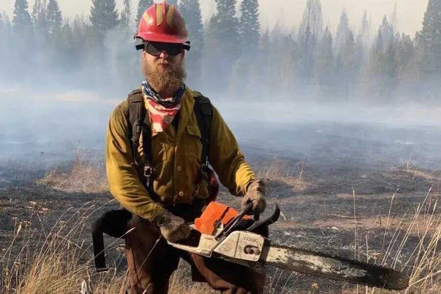 Wildland firefighter Joel Eisiminger out in the field with a chainsaw in hand.