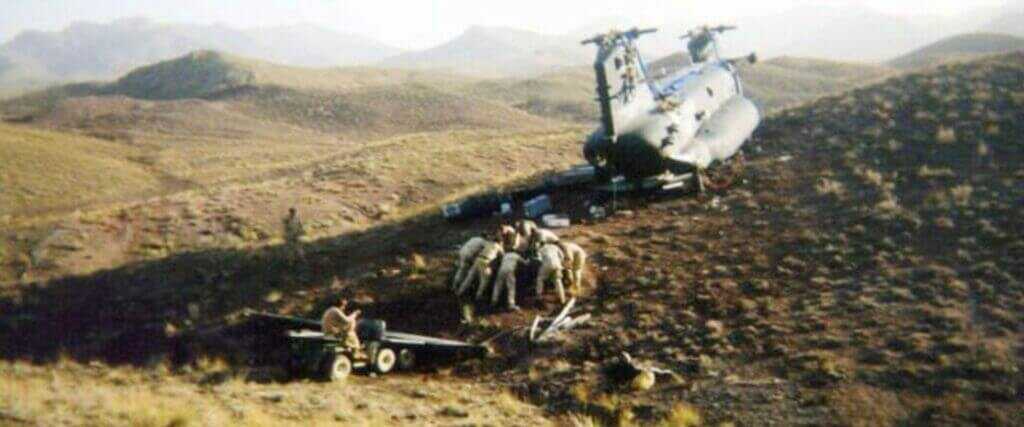 Recovery crew using severed CH-47 rotor blades as ramps to salvage one engine from the wreck