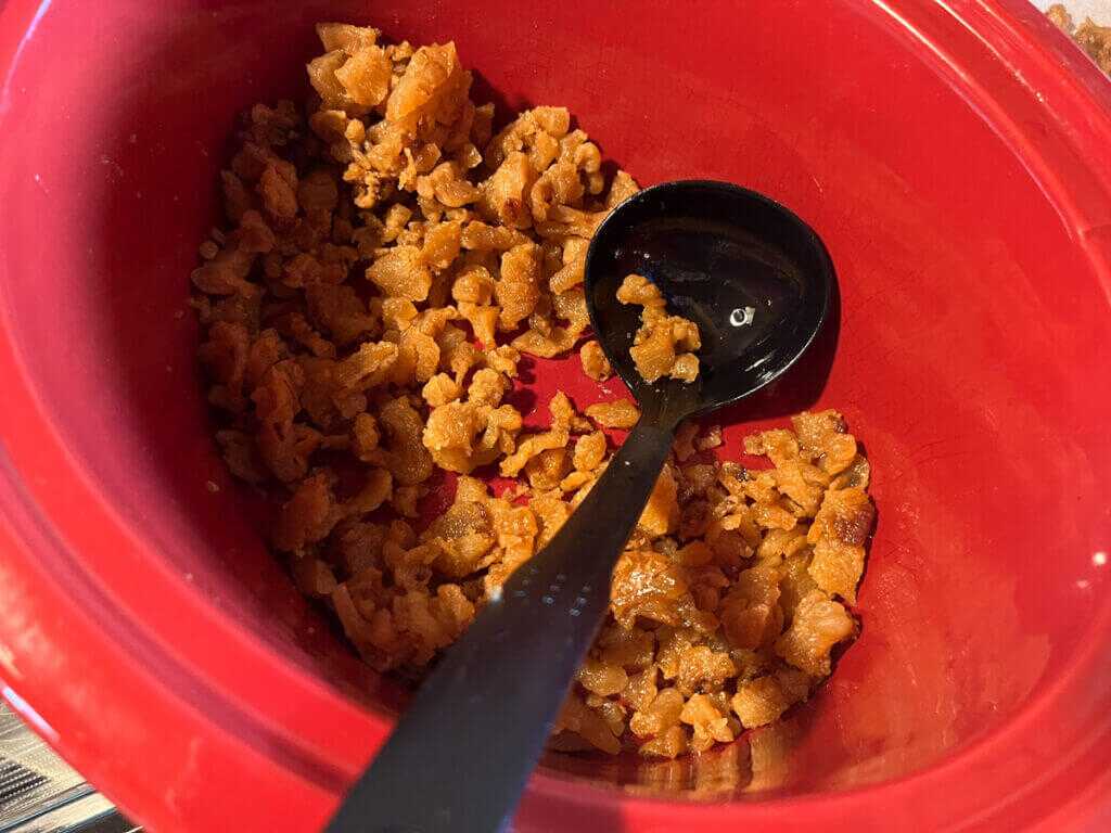Finished bear cracklings in a crock pot with a ladle after rendering wild bear fat