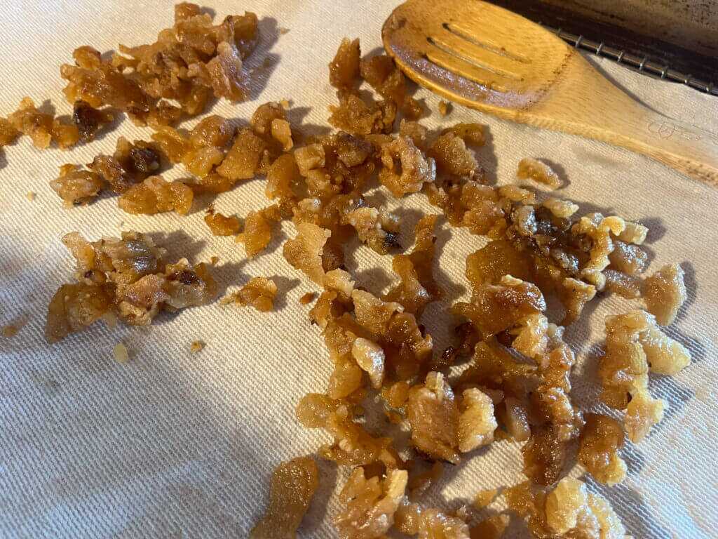 Seasoned bear cracklings cooling on a paper towel with a wooden spoon in the background