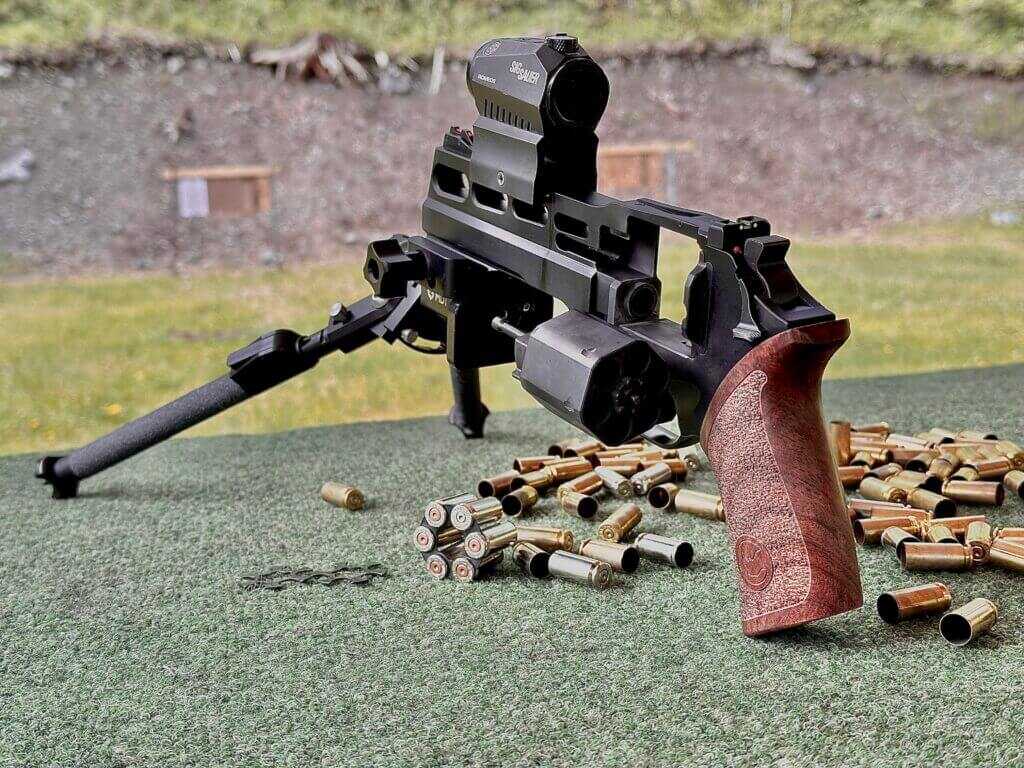 Chiappa Rhino 60 DS 10mm on a shooting bench with bipod, red dot, moon clips, and spent casings for accuracy testing