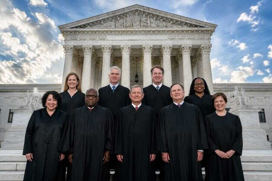 Nine U.S. Supreme Court justices stand in front of the Supreme Court building in Washington, D.C., as the court prepares to hear major challenges to state assault weapon bans.