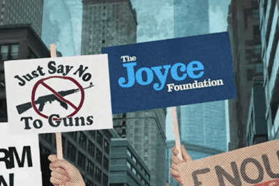 Gun-control demonstrators hold a Joyce Foundation sign and a sign reading Just Say No to Guns