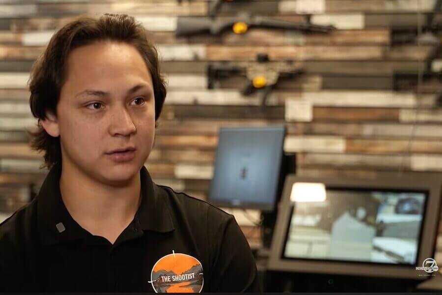 An employee at The Shootist gun store in Englewood, Colorado, discusses the impact of Colorado's new SB 25-003 semiautomatic firearm law as rifles are displayed behind him.
