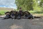 Carter J. Hickey poses behind several illegally taken wild turkeys in an outdoor photo.