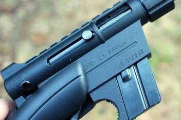 The charging handle, the little nub pictured here, slides back into the bolt, which keeps it out of the way. 