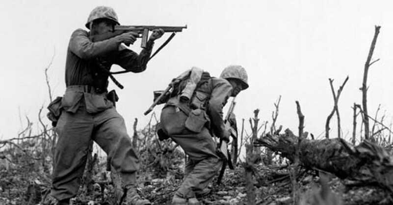 "A Marine of the 1st Marine Division draws a bead on a Japanese sniper with his tommy-gun as his companion ducks for cover. The division is working to take Wana Ridge before the town of Shuri. Okinawa, 1945. S.Sgt. Walter F. Kleine. (Marine Corps) Exact Date Shot Unknown NARA FILE #: 127-N-123170 WAR & CONFLICT BOOK #: 1228" 