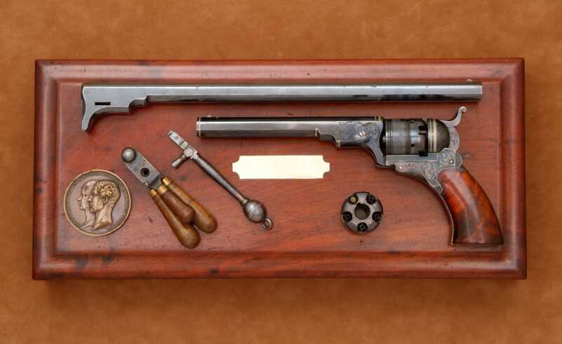 Pictured is an exceptional two barrel cased No. 2 Model. Among options offered with the No. 2 was a 12-inch barrel. A rare presentation, this example has vine scroll engraving, color casehardened frame and hammer, and German silver bands on the barrel and recoil shield. The extra 12-inch barrel was neither engraved nor silver inlayed.